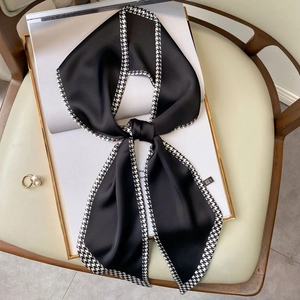 Elegant black long silk scarf with houndstooth pattern displayed on a luxury chair