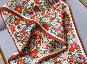 Detalle de un pañuelo de seda con flores rojas y azules y textura de satén suave y lisa