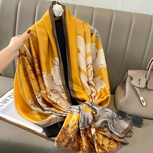 Detailed close-up of golden floral silk scarf with vintage prints on a grey sofa