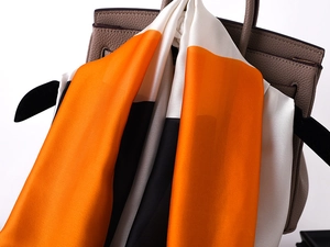Detail of elegant faux silk scarf with orange white and black color block design