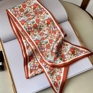 Detalle de un pañuelo de seda estrecho con estampado floral y borde naranja