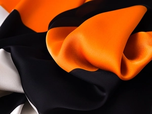 Detailed view of the smooth satin texture and orange-black-white color block scarf
