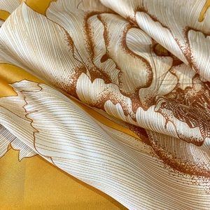 Detail of silk scarf showing yellow floral prints and twill texture on premium fabric