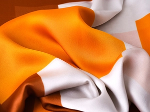 Close-up of bright orange and white geometric silk scarf with luxurious satin texture