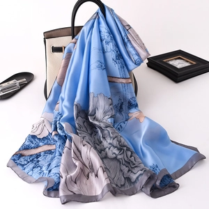 Detail of light blue silk scarf with elegant grey floral prints and smooth texture