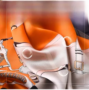 Detail of silk-like scarf fabric featuring classic orange chain and harness patterns