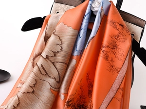 Close-up of elegant floral print silk scarf draped over a luxury leather handbag