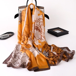 Detail of yellow silk scarf with floral and vintage building prints draped over a bag