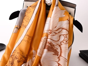 Detailed texture of ginger silk scarf with floral landscape print on clothes hanger