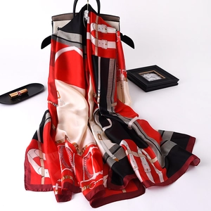 Macro view of satin scarf with equestrian chain print draped on a beige handbag