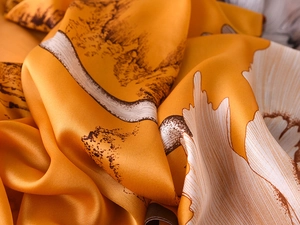 Detailed view of silky orange fabric with vintage oriental landscape and floral prints