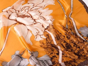 Detailed macro view of ginger yellow silk scarf with peony flowers and castle patterns