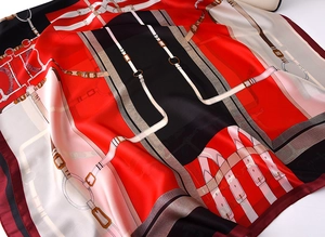 Detailed close-up of silk scarf showing equestrian chain patterns and red satin texture