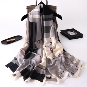 Detail of silk scarf with classic horse harness patterns draped over a luxury handbag