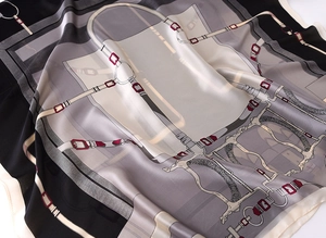 Detailed view of silk-like scarf with equestrian chain patterns and red buckle accents