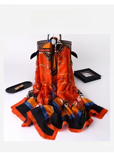 Detail of luxury silk scarf with orange equestrian horsebit patterns draped on a handbag