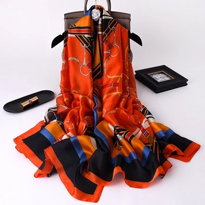 Detail of orange equestrian print silk scarf draped over a classic handbag