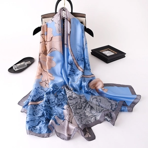 Sky blue silk scarf with classical floral print draped on a handbag and hanger