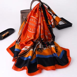 Detail of silk scarf with equestrian patterns draped over a stylish grey handbag