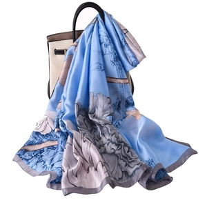 Elegant light blue silk scarf with floral peony prints draped over a beige handbag