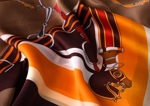 Detailed view of silk scarf fabric showing equestrian prints and smooth satin texture