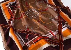 Close-up of silk-like scarf with orange and brown belt buckle patterns and glossy texture