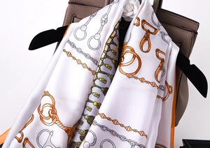 Detail of silk scarf with equestrian prints hung on a leather bag and velvet hanger