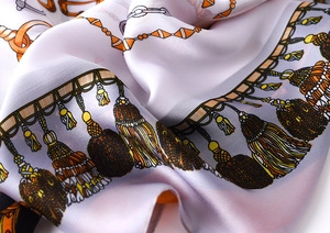 Detailed macro shot of silky purple scarf featuring vintage golden chain print and tassels