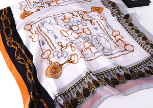 Detailed close-up of silk square scarf featuring equestrian chain and tassel patterns