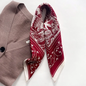 Detail eines Seidenschals mit rotem Toile-de-Jouy-Drachendruck auf braunem Strickstoff