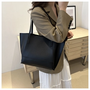 Black large-capacity tote bag with fine grain texture shown from a side view