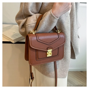 Detailed close-up of brown textured leather bag with gold buckle and stylish flap