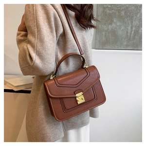 Detail view of brown faux leather handbag featuring lizard texture and gold metal buckle