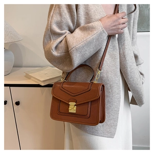 Close-up of brown lychee texture leather bag with elegant gold square lock and handle