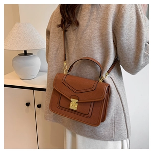 Detailed close-up of caramel lychee grain leather crossbody bag with golden metal lock