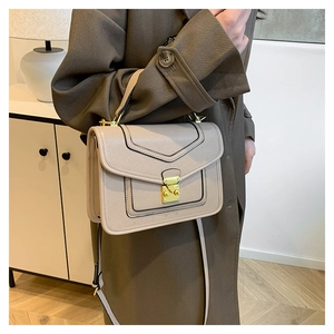 Detailed close-up of a beige textured leather crossbody bag with a gold metal clasp