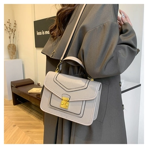 Side view of grey leather handbag with golden buckle and adjustable strap