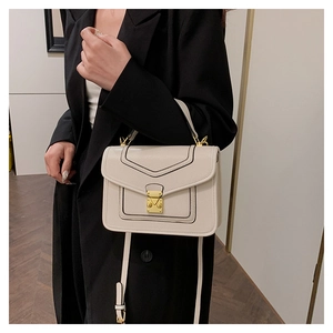 Detail of cream crossbody bag with V-shaped stitching and golden metal clasp on a model