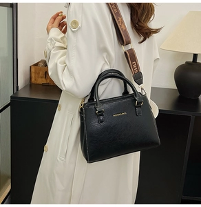 Model view of black lychee grain tote bag with decorative wide fabric shoulder strap