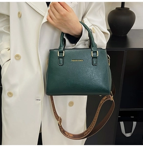 Detail of dark green leather tote bag with white stitching and stylish wide strap