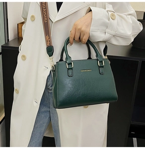 Macro view of dark green leather handbag with embroidery strap and golden fashion text