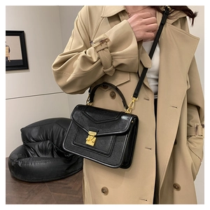 Elegant black lychee leather crossbody bag shown with gold lock detail on a model