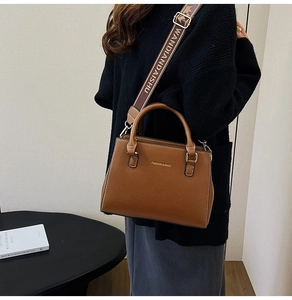 Macro detail of brown leather Boston bag with fashion logo and gold hardware details