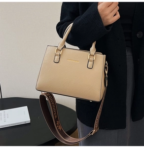 Detail of khaki tote bag with fashion lettering and decorative woven shoulder strap