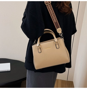 Detail of beige textured tote bag with golden lettering and stylish wide fabric shoulder strap