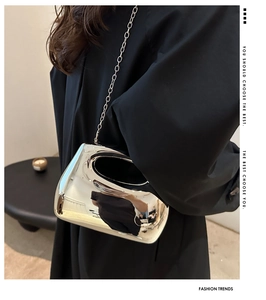 Detail of silver mirror acrylic handbag featuring round cutout handle and metal chain