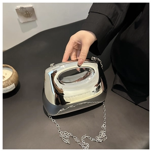 Macro shot of silver mirrored acrylic clutch featuring chrome finish and metallic chain