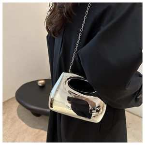 Detail of silver mirror acrylic handbag with oval cutout handle and metal chain strap