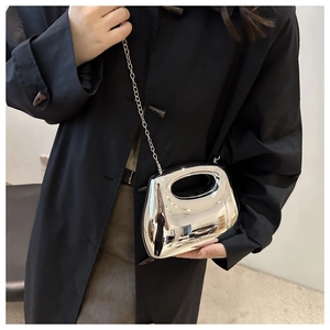 Macro shot of silver pebble-shaped acrylic bag with sleek metallic finish and chain strap
