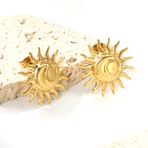 Bohemian gold stainless steel sun and moon stud earrings on a beige stone display